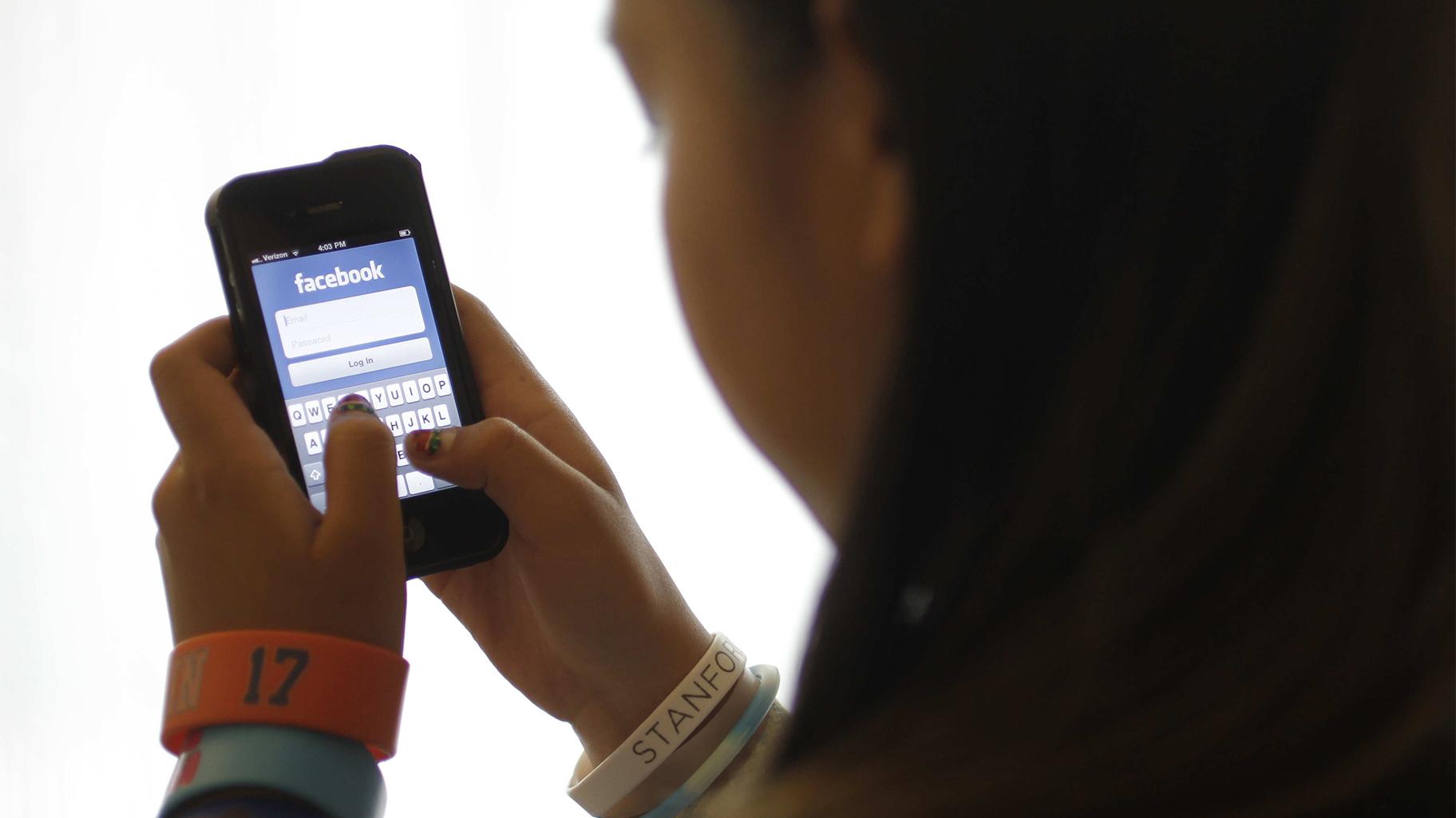 In this June 4, 2012, file photo, an unidentified 11-year-old girl logs into Facebook on her iPhone at her home in Palo Alto, Calif. (AP Photo / Paul Sakuma, File)