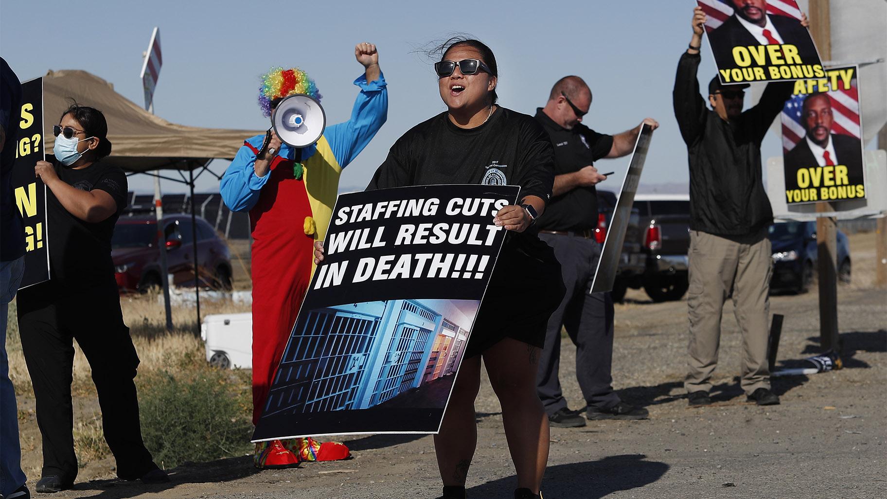 Noni Ahulau, from Honolulu, along with others, protests staffing shortages at the Federal Correctional Institution at Mendota, Monday, May 17, 2021, near the facility, in Mendota, Calif. The signs being displayed and held, at right, show a picture of FCI Mendota Warden Douglas K. White. (AP Photo / Gary Kazanjian)