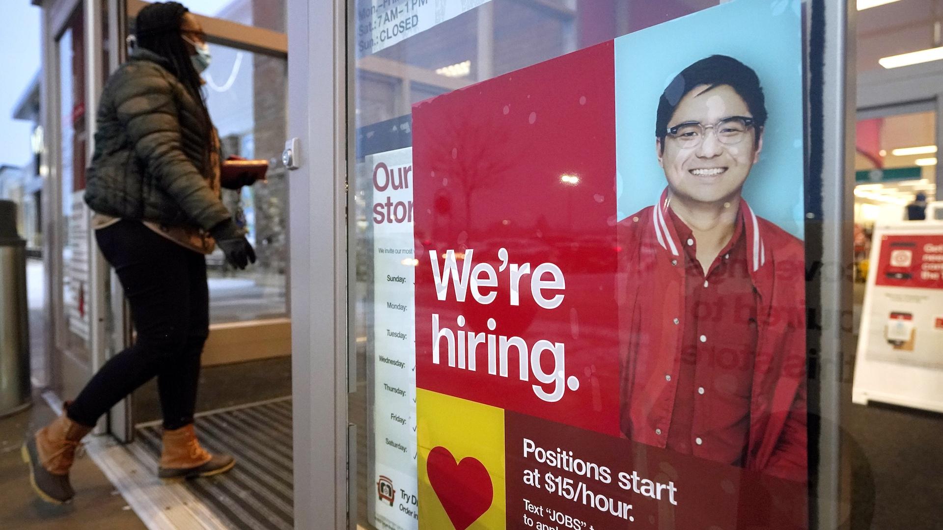 In this Feb. 9, 2021 file photo, a passer-by walks past an employment hiring sign while entering a Target store location, in Westwood, Mass. (AP Photo/Steven Senne, File)