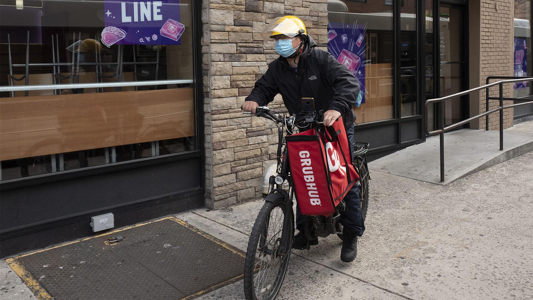 In this April 21, 2021 file photo, a delivery man bikes with a food bag from Grubhub in New York. (AP Photo / Mark Lennihan, File)