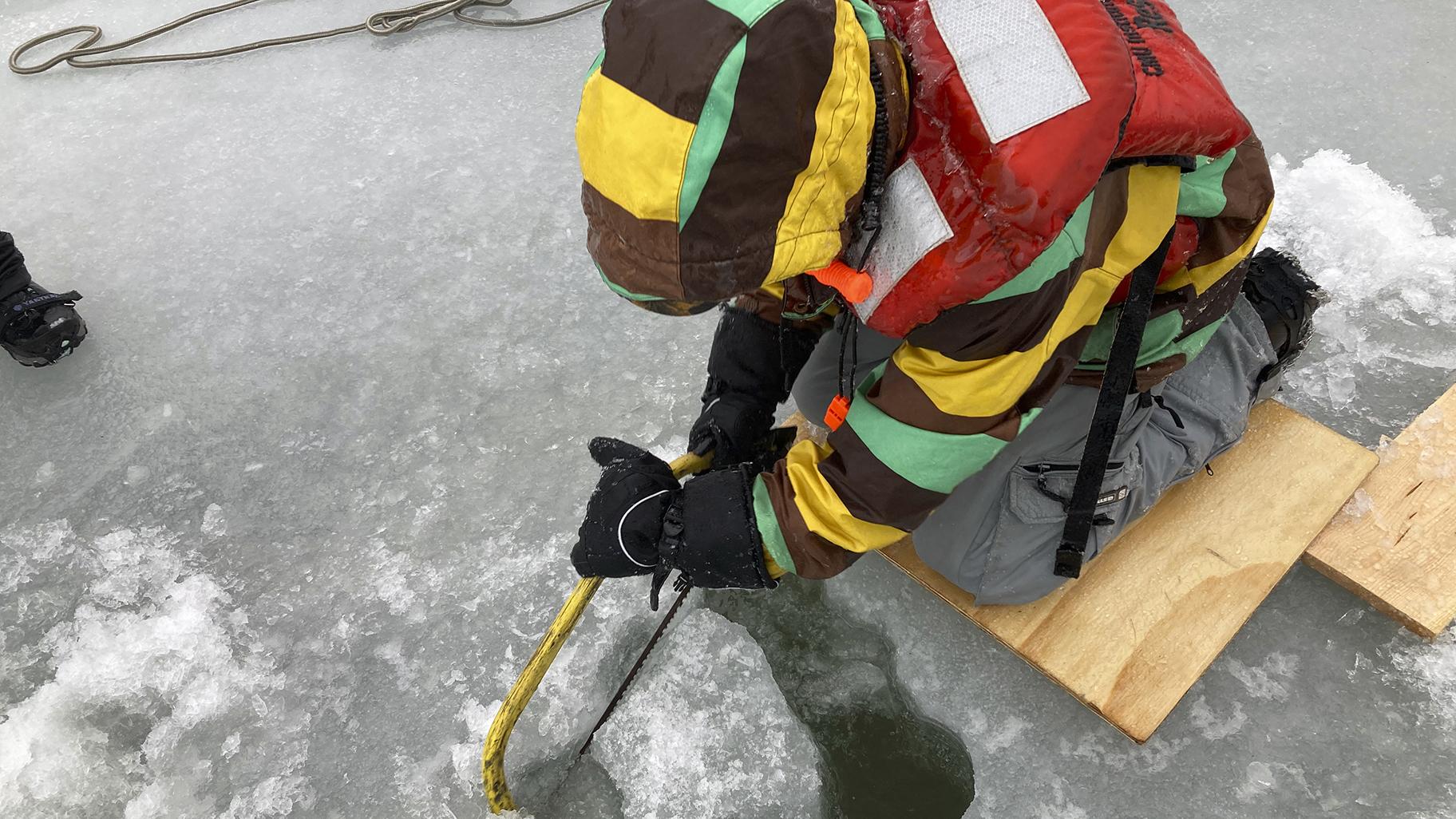 Matt Sand, wetland field crew leader for the Great Lakes Restoration Initiative, saws into the frozen surface of Lake Huron’s Saginaw Bay on Tuesday, Feb. 22, 2022 in Standish, Mich. (AP Photo / Mike Householder)