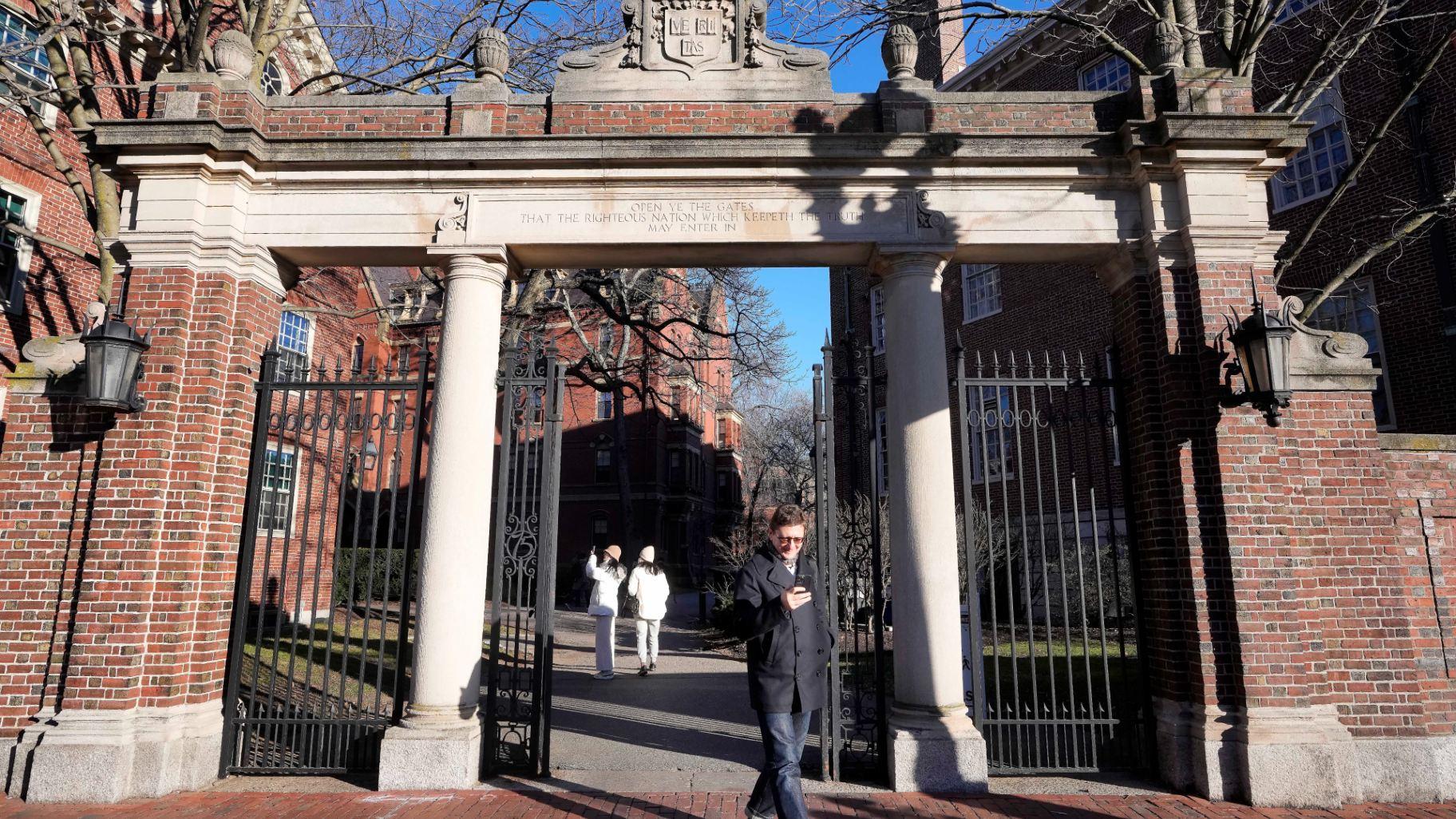 A passer-by walks through a gate to the Harvard University campus, Tuesday, Jan. 2, 2024, in Cambridge, Mass. (Steven Senne / AP Photo)