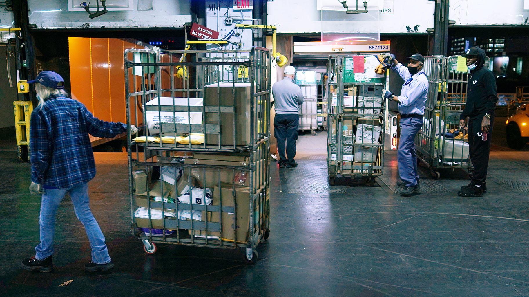 Workers unload packages and letters from mail trucks at the United States Postal Service sorting and processing facility, Thursday, Nov. 18, 2021, in Boston. (AP Photo / Charles Krupa)