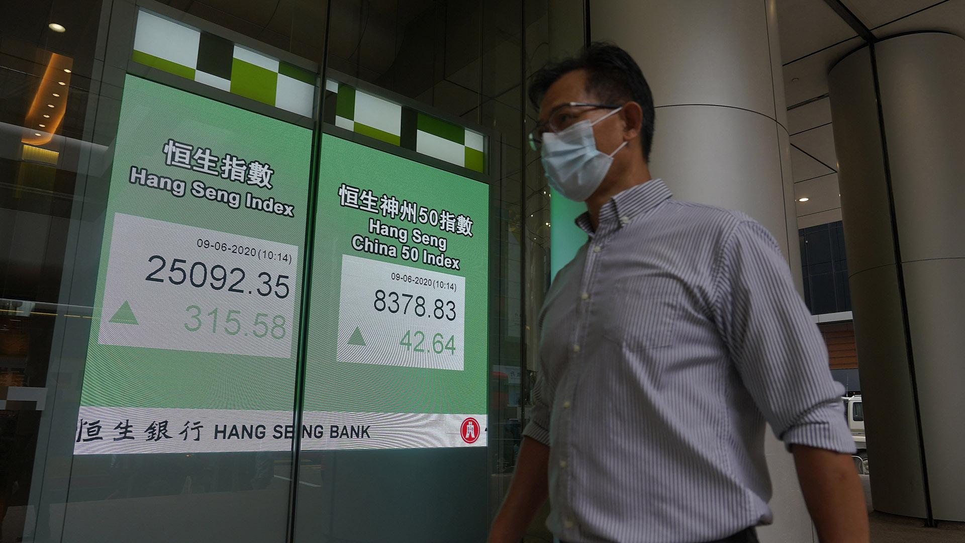 A man wearing a face mask walks past a bank electronic board showing the Hong Kong share index at Hong Kong Stock Exchange Tuesday, June 9, 2020. Asian shares were mixed on Tuesday after the Nasdaq hit a record high. (AP Photo / Vincent Yu)
