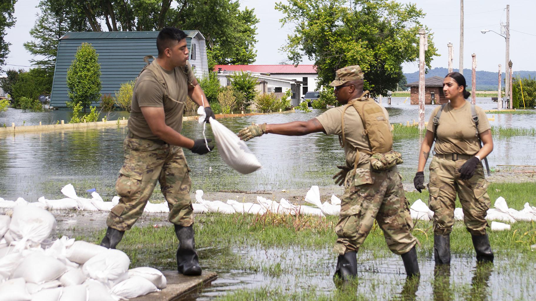 Illinois National Guard soldiers move sandbags through flood waters at East Cape Girardeau, Illinois, on June 12, 2019, as they construct a sandbag levee to control flooding in the community. (Barbara Wilson / Illinois National Guard) 