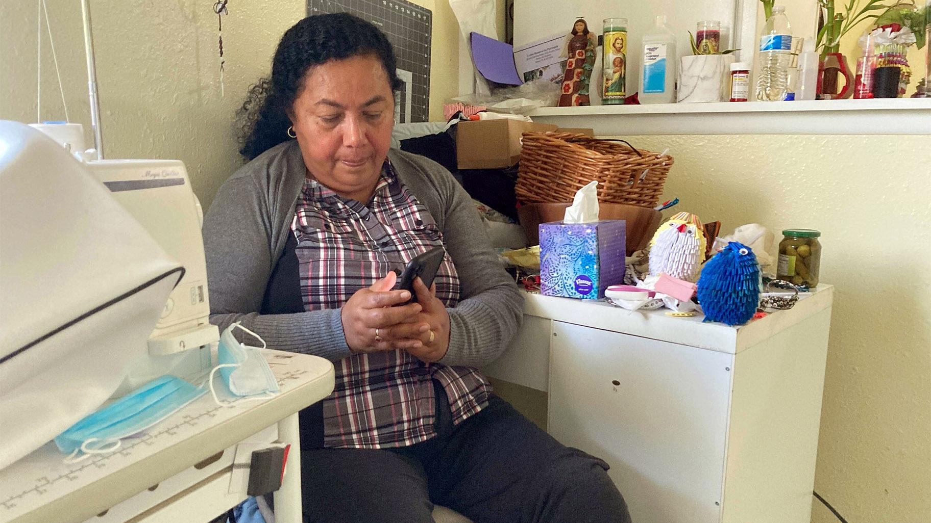 Rosalidia Dardon, 54, looks at a picture of her daughter in El Salvador as she sits in a refugee house in Texas, awaiting asylum or a protected immigration status on Nov. 4, 2021.  (Acacia Coronado / Report for America via AP)