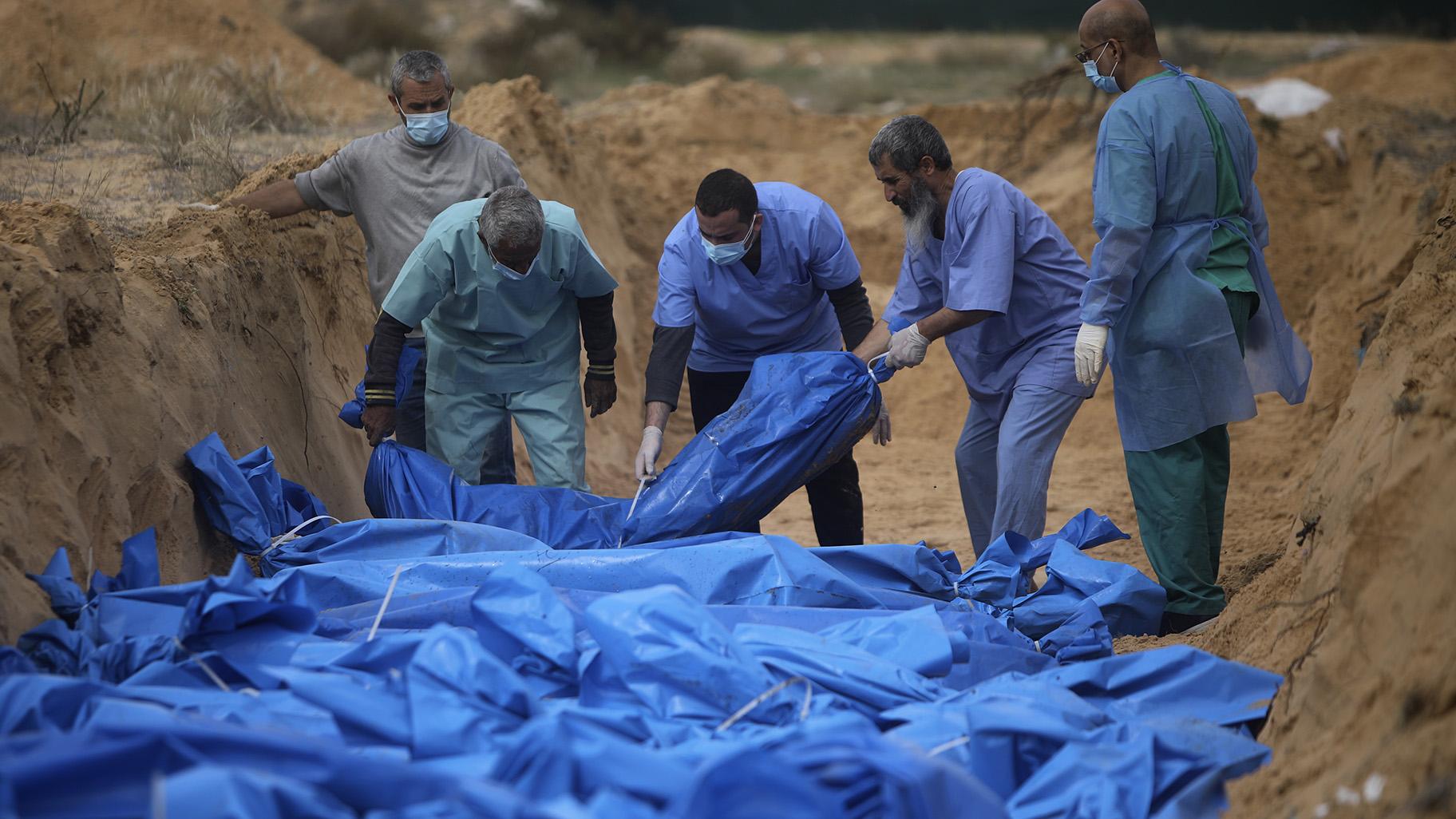 Palestinians bury people killed in the Israeli bombardment who were brought from the Shifa hospital, in a mass grave in the town of Khan Younis, southern Gaza Strip, Wednesday, Nov. 22, 2023. (AP Photo /Mohammed Dahman)