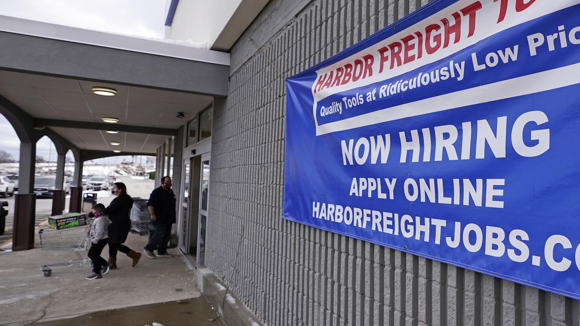 In this Dec. 10, 2020 file photo, a "Now Hiring" sign hangs on the front wall of a Harbor Freight Tools store in Manchester, N.H. (AP Photo/Charles Krupa, File)