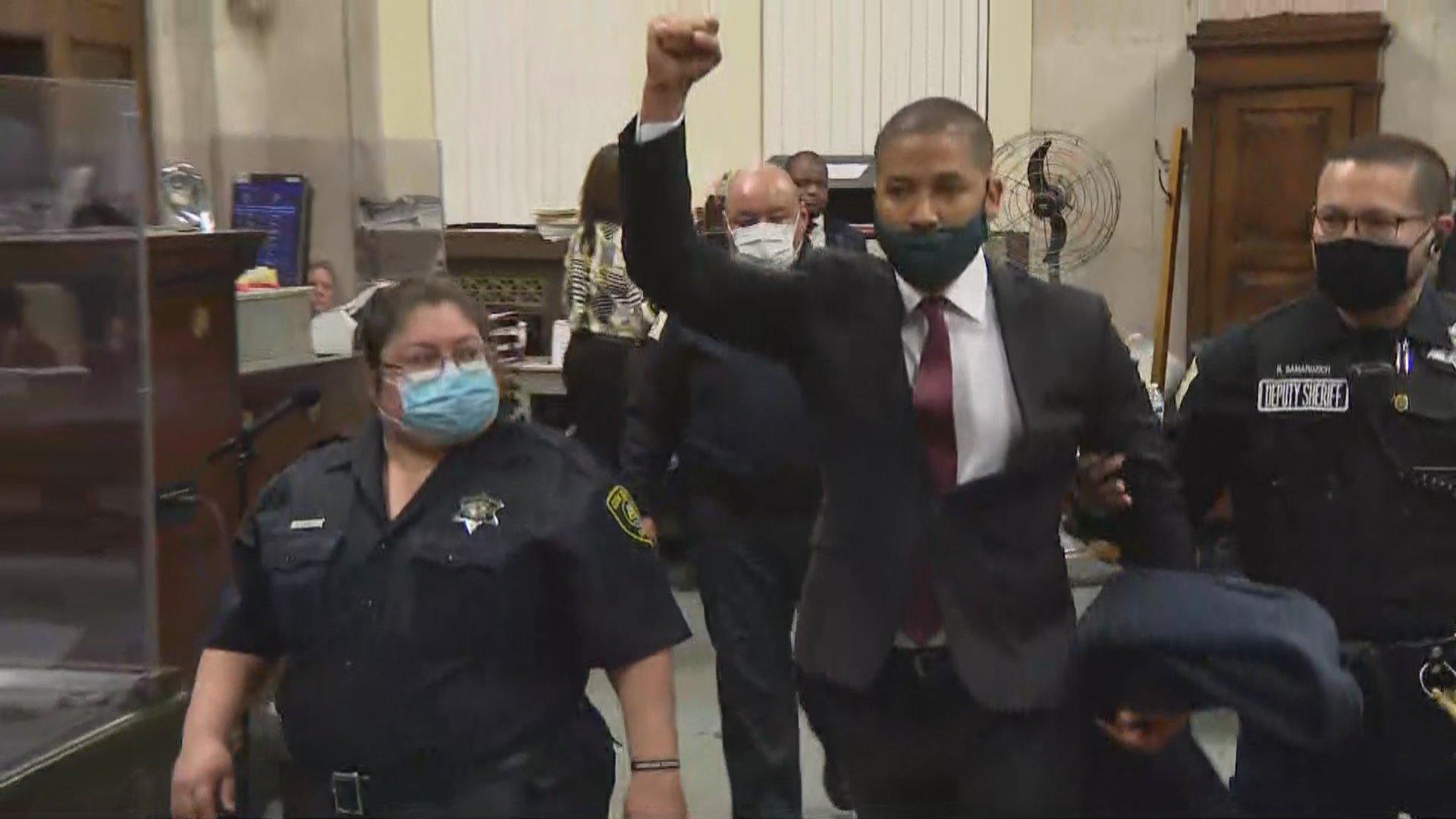 Jussie Smollett raises his hand while proclaiming his innocence as he is taken out of the courtroom at the Leighton Criminal Court Building to begin his 150-day jail sentence on March 10, 2022. (WTTW News)