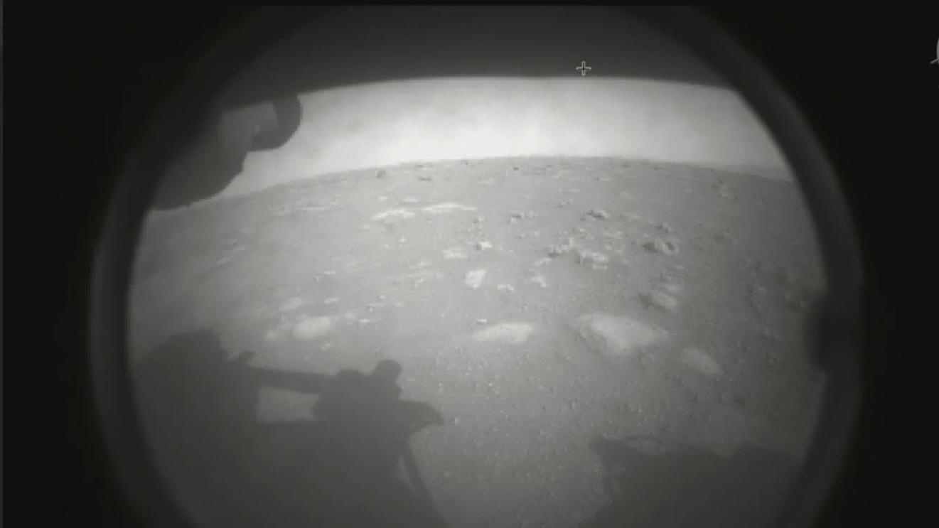 The first image NASA’s Perseverance rover sent back after touching down on Mars on Feb. 18, 2021. The view, from one of Perseverance’s Hazard Cameras, is partially obscured by a dust cover. (NASA / JPL-Caltech)