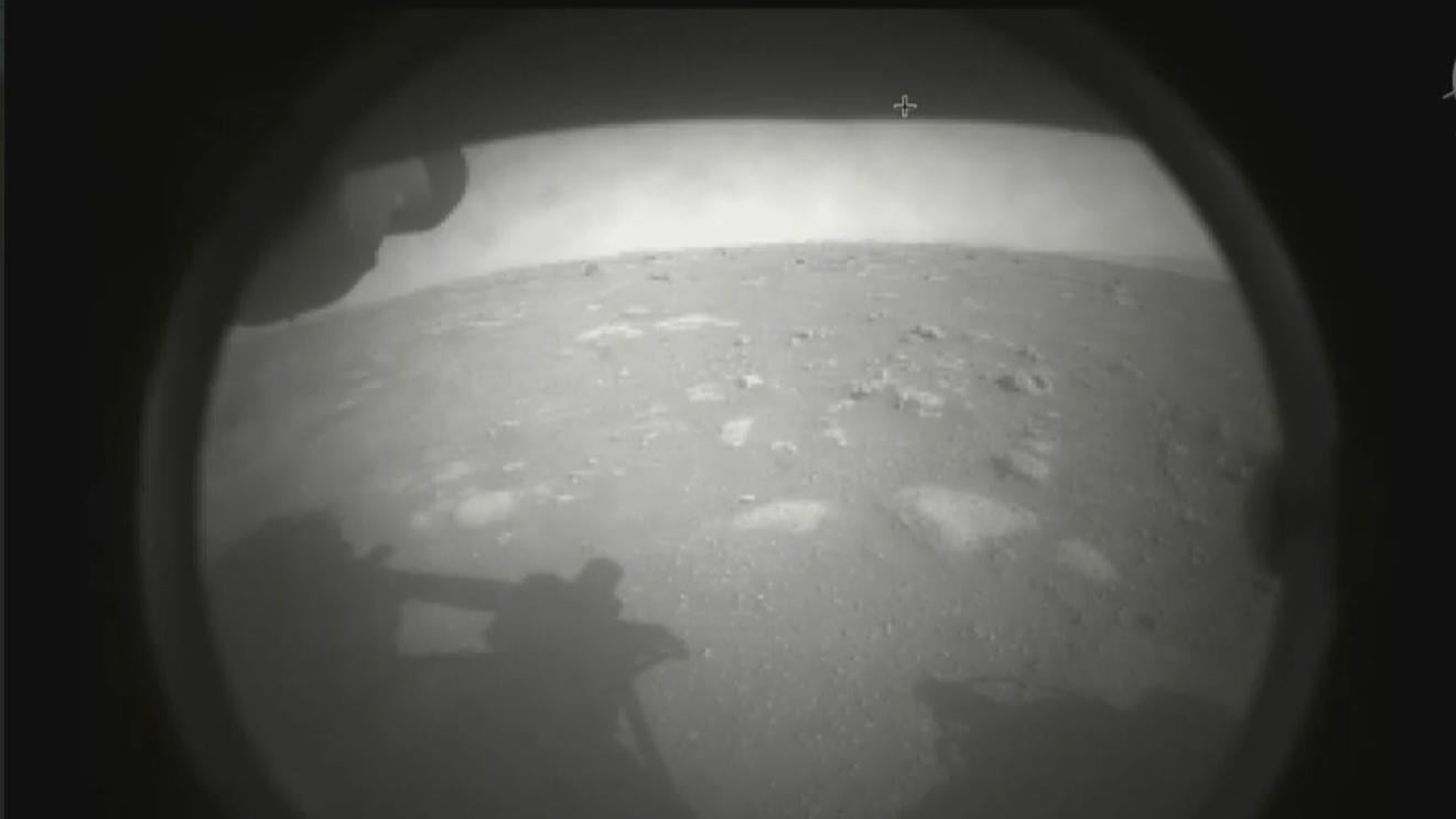 The first image NASA’s Perseverance rover sent back after touching down on Mars on Feb. 18, 2021. The view, from one of Perseverance’s Hazard Cameras, is partially obscured by a dust cover. (NASA / JPL-Caltech)