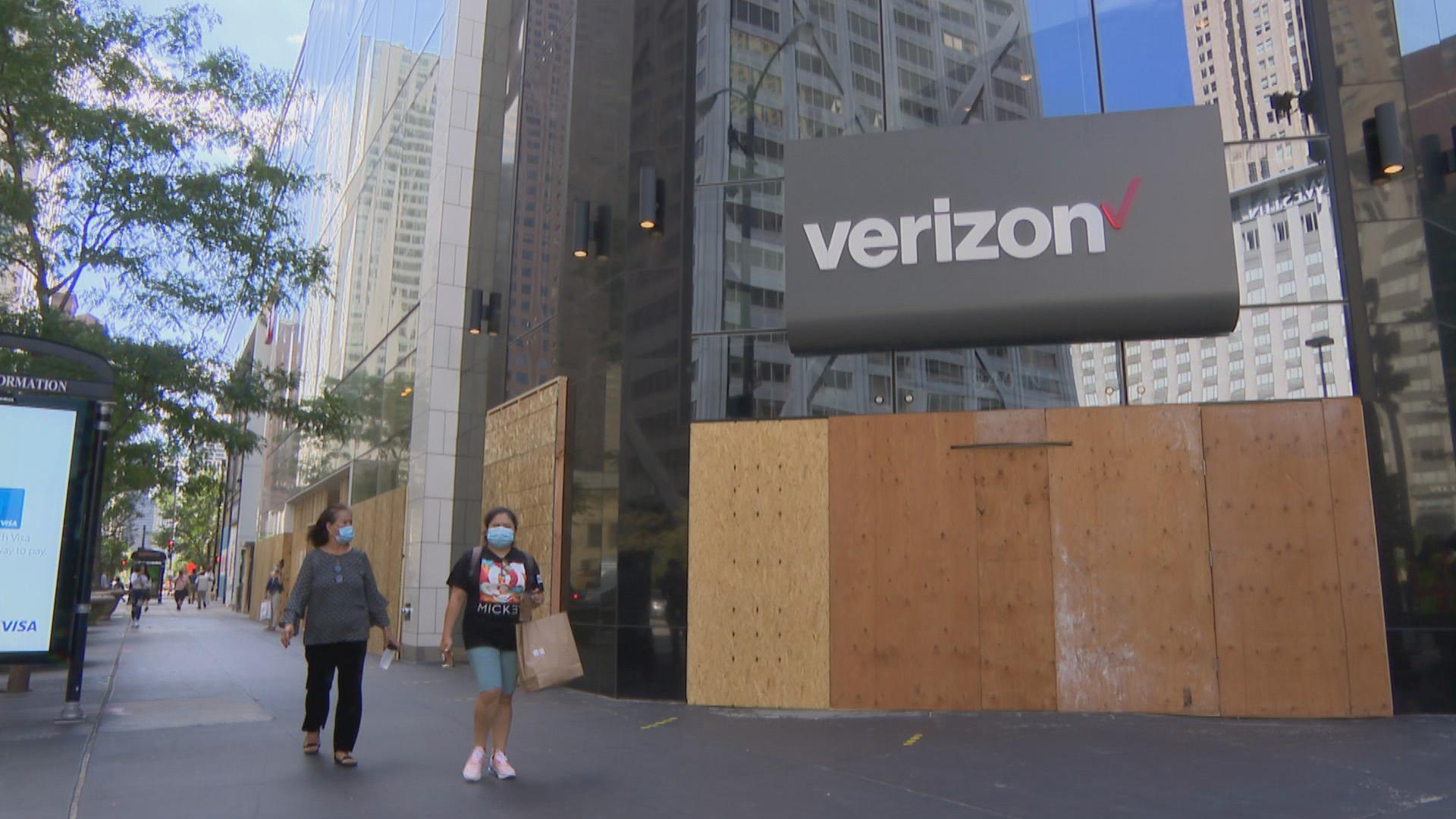 Shoppers walk past a string of boarded-up stores along Michigan Avenue on Friday, Aug. 28, 2020. Shopping along the retail-heavy strip and elsewhere in the city has taken a hit from the pandemic and also recent looting due to unrest. (WTTW News)