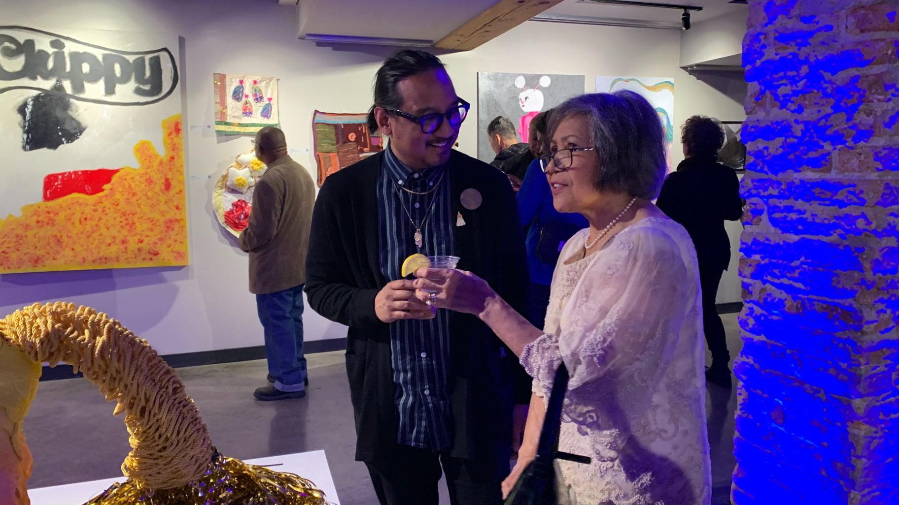 Artist James Bulosan, left, and artist Tita Recometa-Brady, having a conversation at the “More than Lumpia” art exhibit on Oct. 6 at the Epiphany Center for the Arts. (WTTW News / Eunice Alpasan)