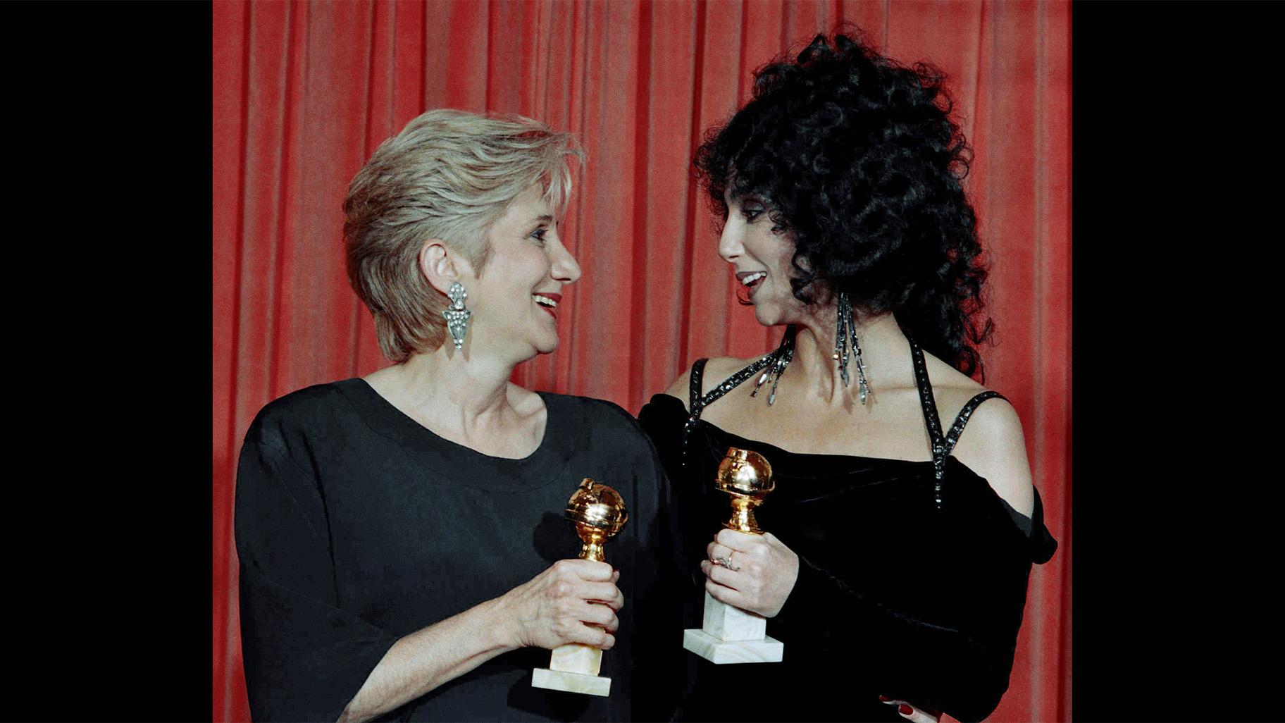 In this Jan. 24, 1988 file photo, actress Olympia Dukakis, winner of a Golden Globe for “Best Performance in a Supporting Role” and Cher, winner of the “Best Performance by an Actress in a musical or comedy,” hold the awards they received for performances in the hit movie “Moonstruck” at the Beverly Hilton Hotel. (AP Photo / Reed Saxon, File)
