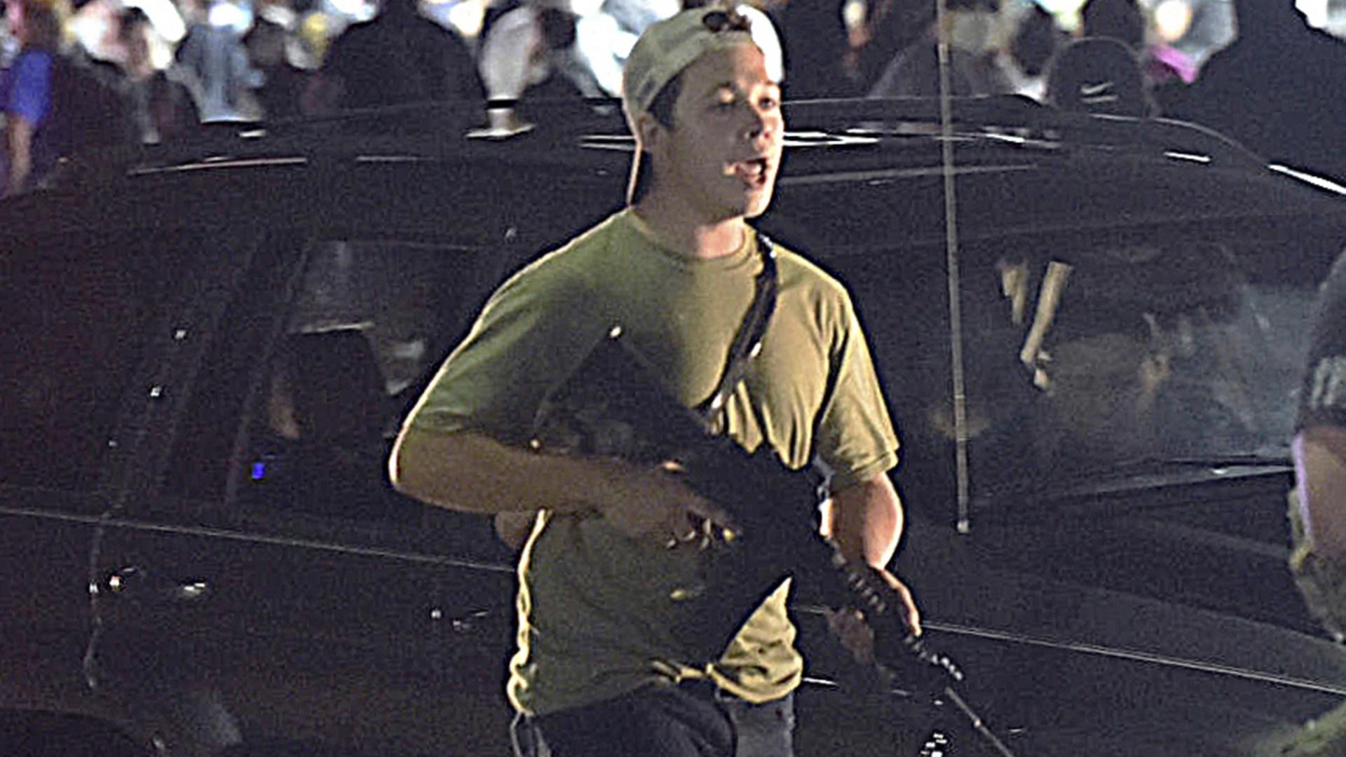 In this Tuesday, Aug. 25, 2020 file photo, Kyle Rittenhouse carries a weapon as he walks along Sheridan Road in Kenosha, Wis., during a night of unrest following the weekend police shooting of Jacob Blake. (Adam Rogan/The Journal Times via AP, File)