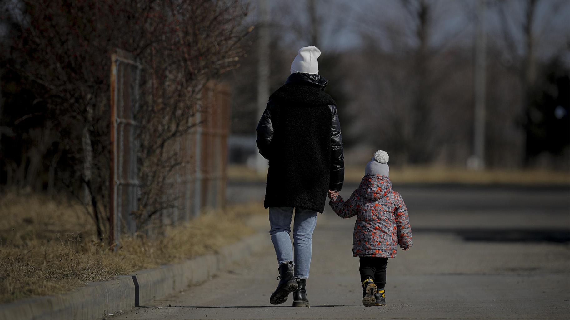 A woman holds a child's hand after crossing the border from Ukraine at the Romanian-Ukrainian border, in Siret, Romania, Friday, Feb. 25, 2022.  (AP Photo / Andreea Alexandru)