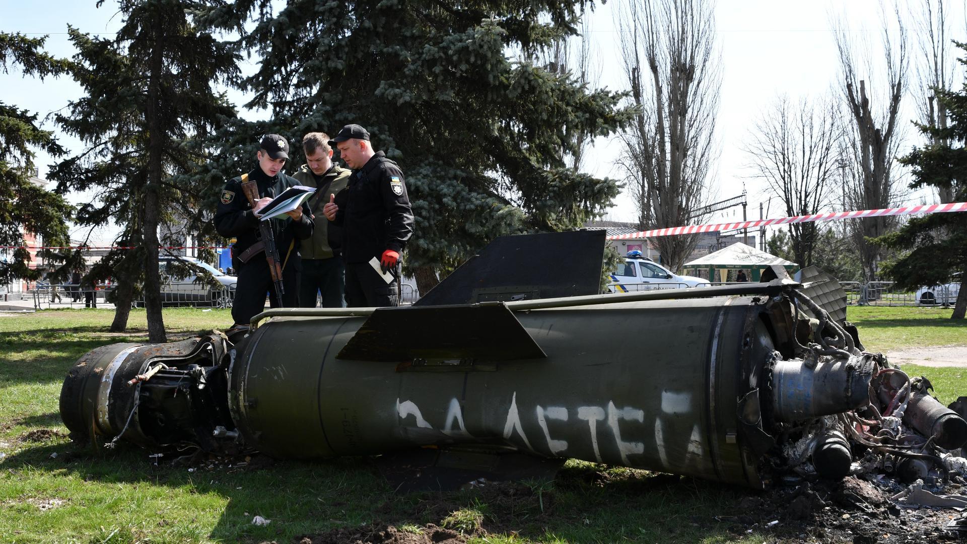 Ukrainian servicemen stand next to a fragment of a Tochka-U missile with a writing in Russian “For children”, on the grass after Russian shelling at the railway station in Kramatorsk, Ukraine, Friday, April 8, 2022. (AP Photo / Andriy Andriyenko)