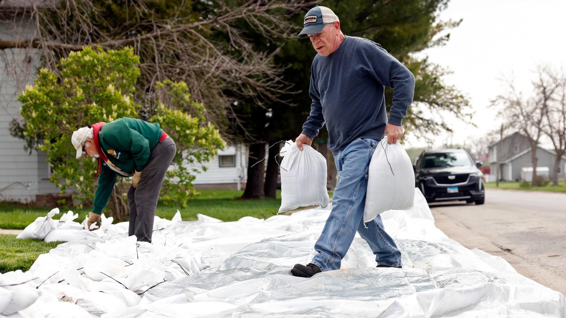 Sparky Donahue place sandbags outside a home on Second Street, Tuesday, April 25, 2023, in Buffalo, Iowa. The river front town, 20 minutes south of Davenport, Iowa, is preparing for flooding from the Mississippi River.(Nikos Frazier / Quad City Times via AP)