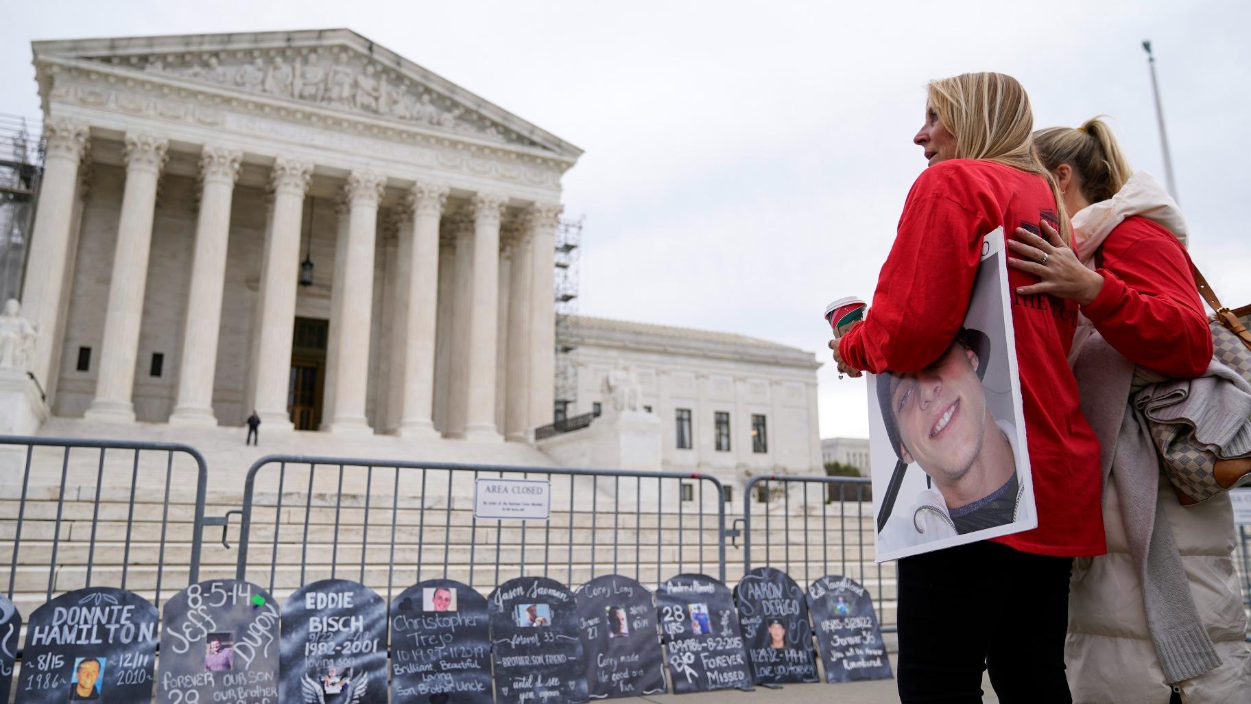 Jen Trejo holds a photo of her son Christopher as she is comforted outside the Supreme Court Monday, Dec. 4, 2023, in Washington. Her son was 32 when he died and she said about Purdue Pharma and the Sackler family, “You can’t just kill my child and just pay a fine.” (AP Photo / Stephanie Scarbrough)