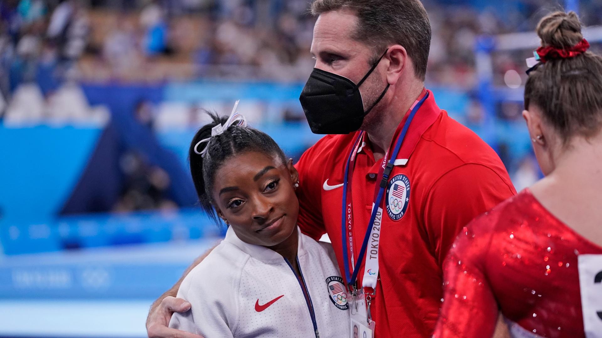 Coach Laurent Landi embraces Simone Biles, after she exited the team final with apparent injury, at the 2020 Summer Olympics, Tuesday, July 27, 2021, in Tokyo. (AP Photo / Gregory Bull)