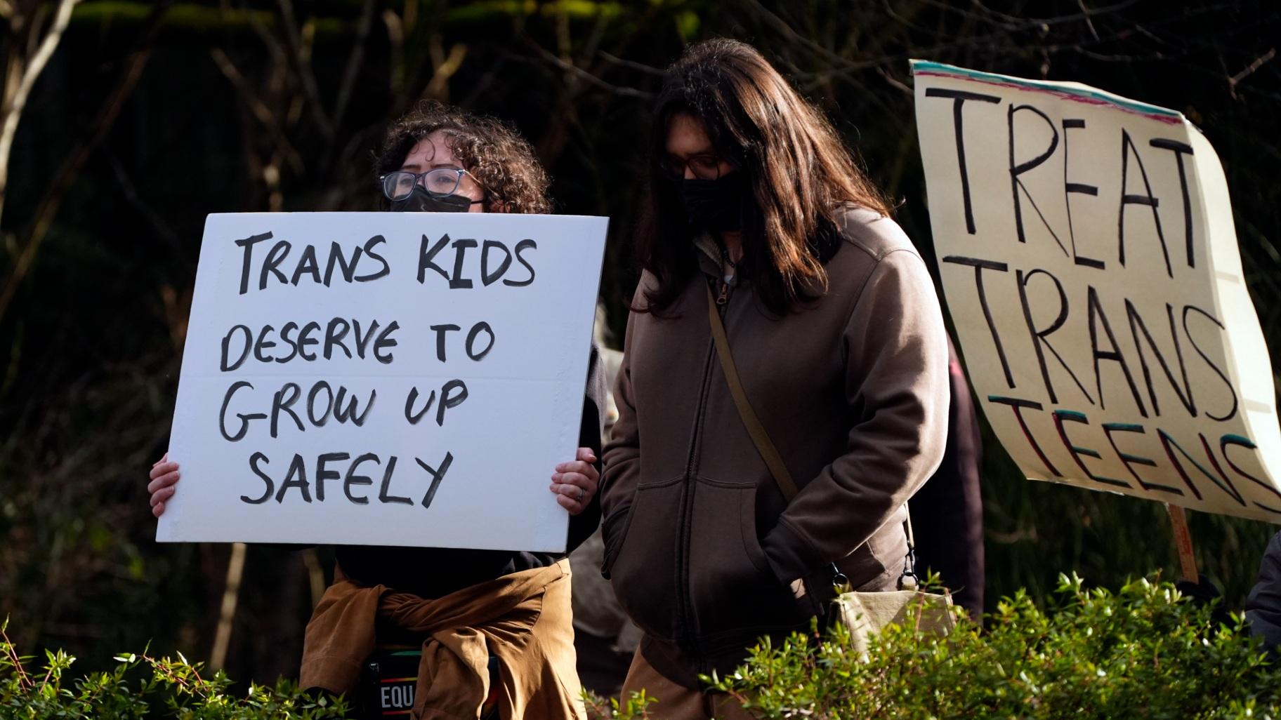 FILE - People wave signs to passing cars during a pro-transgender rights protest outside of Seattle Children's Hospital after the institution postponed some gender-affirming surgeries for minors following an executive order by President Donald Trump, Sunday, Feb. 9, 2025, in Seattle. (Lindsey Wasson / AP Photo, File) FILE - People wave signs to passing cars during a pro-transgender rights protest outside of Seattle Children's Hospital after the institution postponed some gender-affirming surgeries for minors following an executive order by President Donald Trump, Sunday, Feb. 9, 2025, in Seattle. (Lindsey Wasson / AP Photo, File)