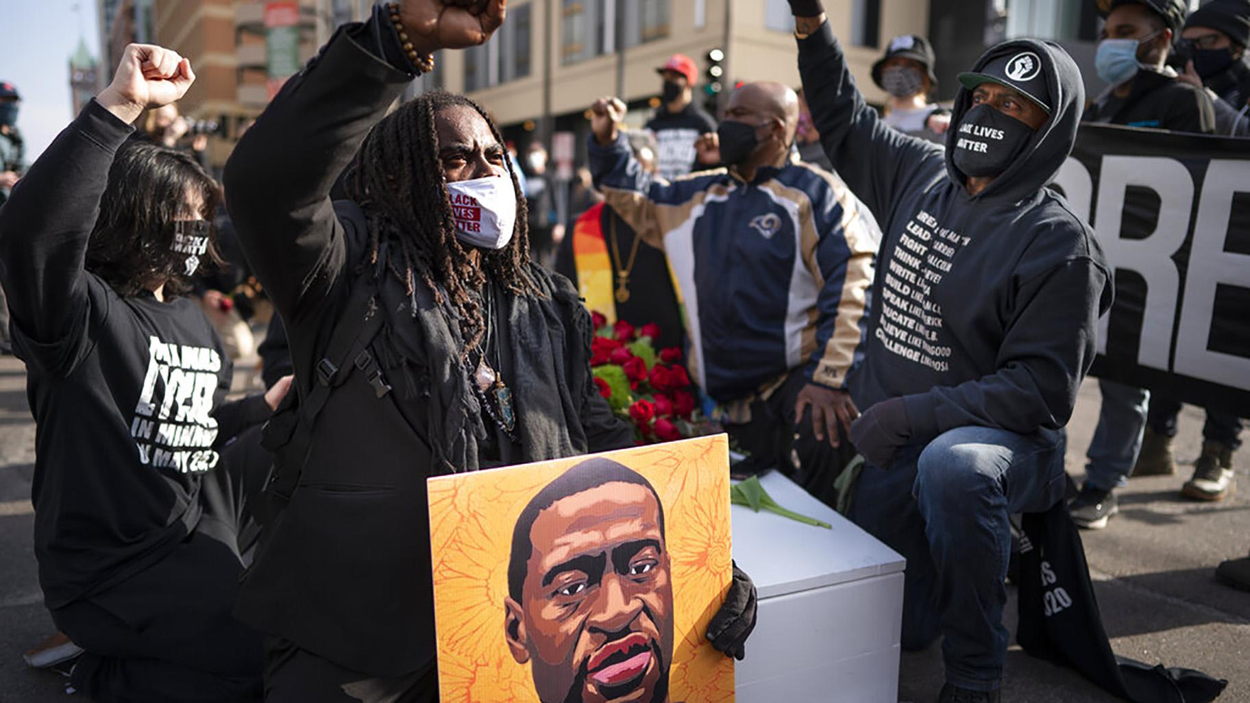 Cortez Rice, left, of Minneapolis, sits with others in the middle of Hennepin Avenue on Sunday, March 7, 2021, in Minneapolis, Minn., to mourn the death of George Floyd a day before jury selection is set to begin in the trial of former Minneapolis officer Derek Chauvin, who is charged in Floyd’s death. (Jerry Holt / Star Tribune via AP)