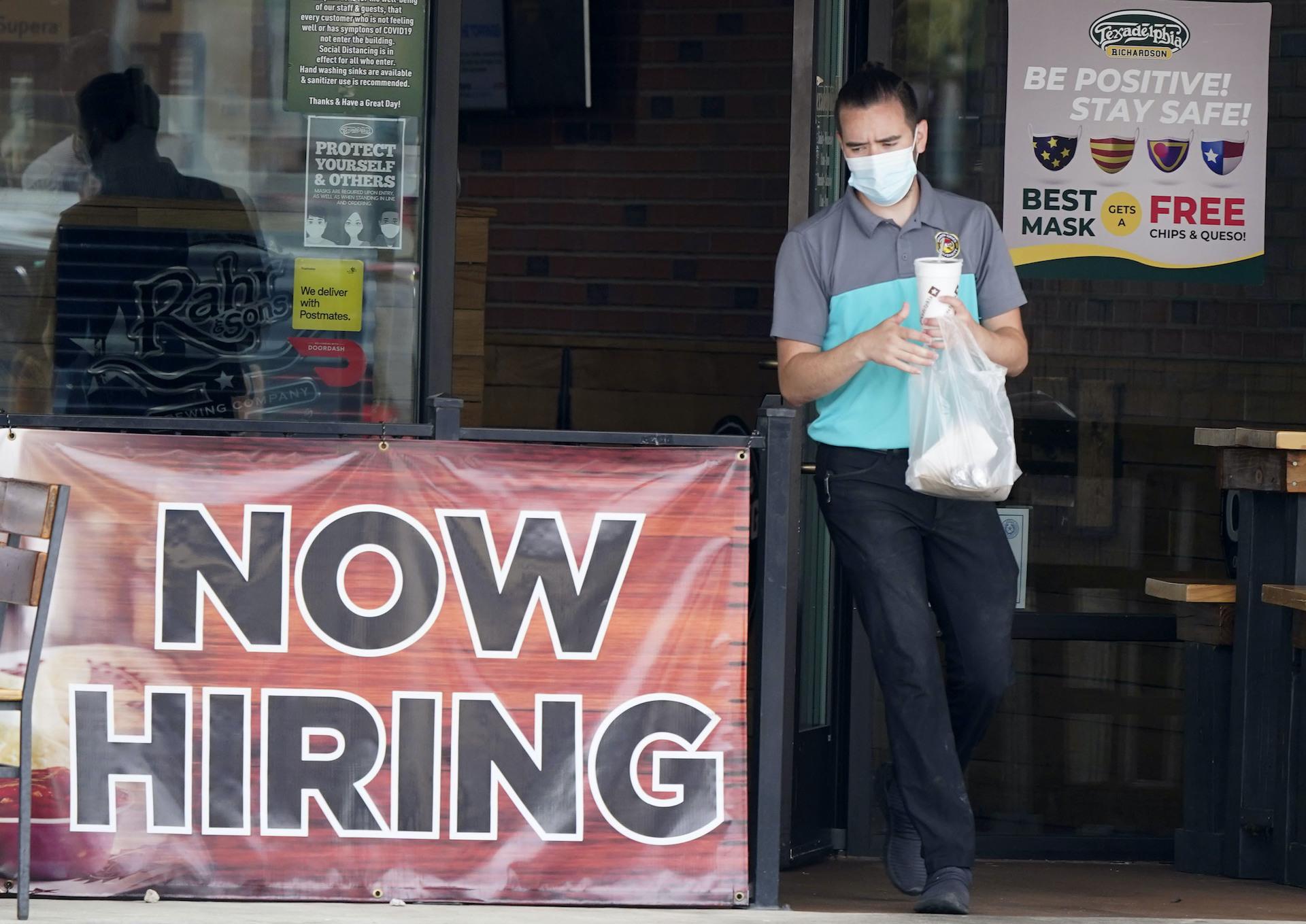 In this Sept. 2, 2020 file photo, a customer wears a face mask as they carry their order past a now hiring sign at an eatery in Richardson, Texas. (AP Photo/LM Otero, File)