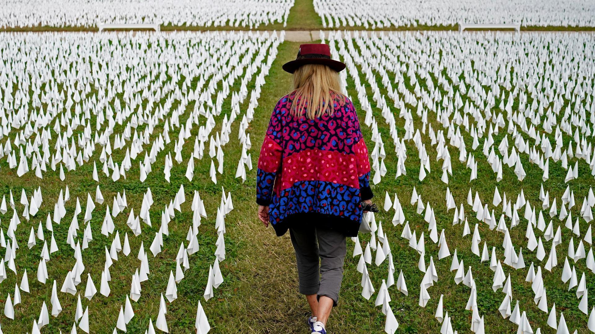 In this Oct. 27, 2020, artist Suzanne Brennan Firstenberg walks among thousands of white flags planted in remembrance of Americans who have died of COVID-19 near Robert F. Kennedy Memorial Stadium in Washington.. (AP Photo / Patrick Semansky, File)