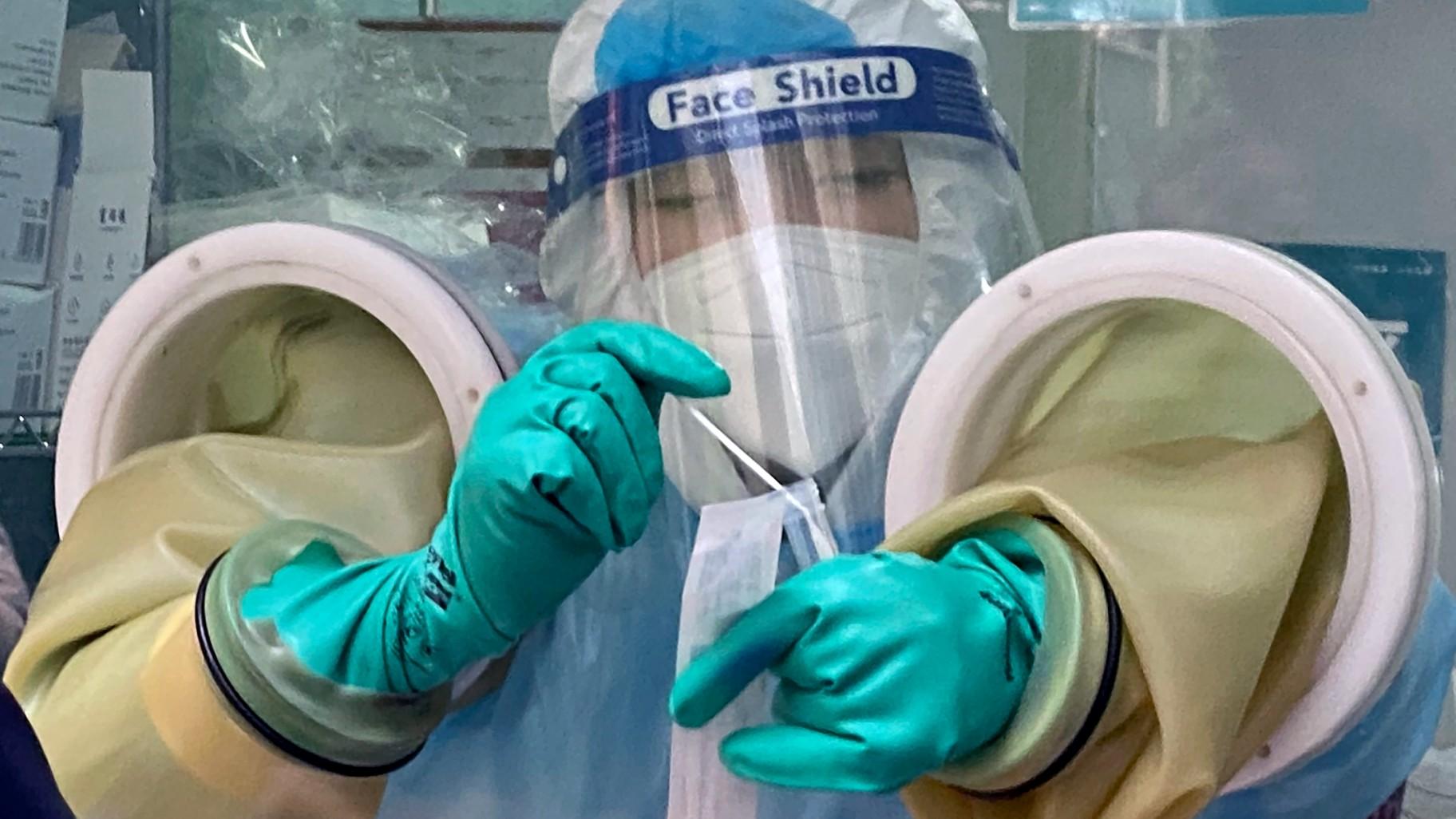 A worker handles a coronavirus test sample at a private testing site in Beijing, Wednesday, Jan. 26, 2022. (AP Photo / Mark Schiefelbein, File)