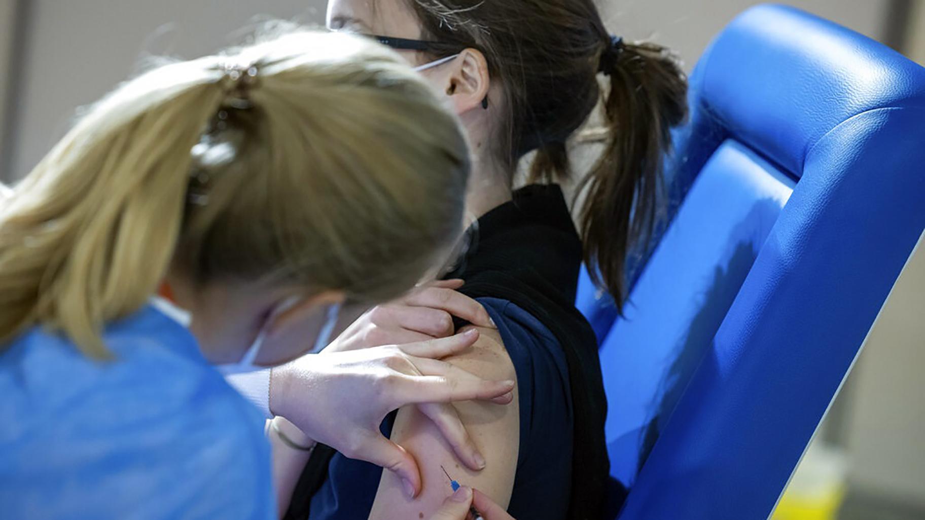 A healthcare worker administers a dose of the AstraZeneca COVID-19 vaccine to a woman at the Brussels Expo center in Brussels, Thursday, March 4, 2021. The Expo is one of the largest vaccination centers in Belgium. (AP Photo / Olivier Matthys)