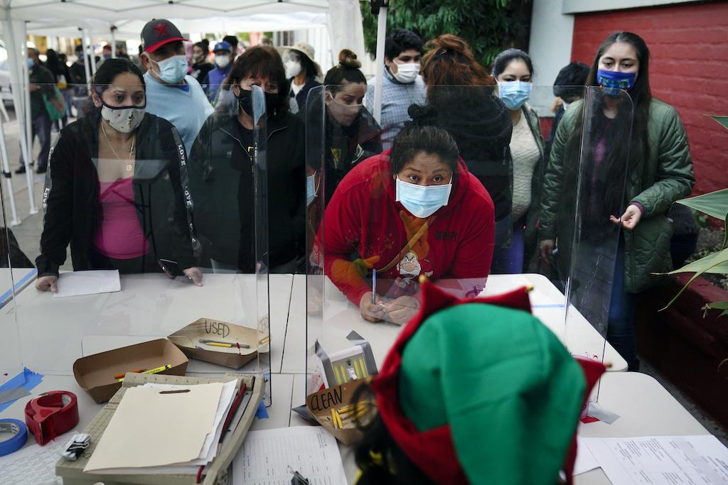 In this Dec. 17, 2020, file photo people check in at a food bank held at Los Angeles Boys & Girls Club in the Lincoln Heights neighborhood of Los Angeles. (AP Photo/Jae C. Hong,File)