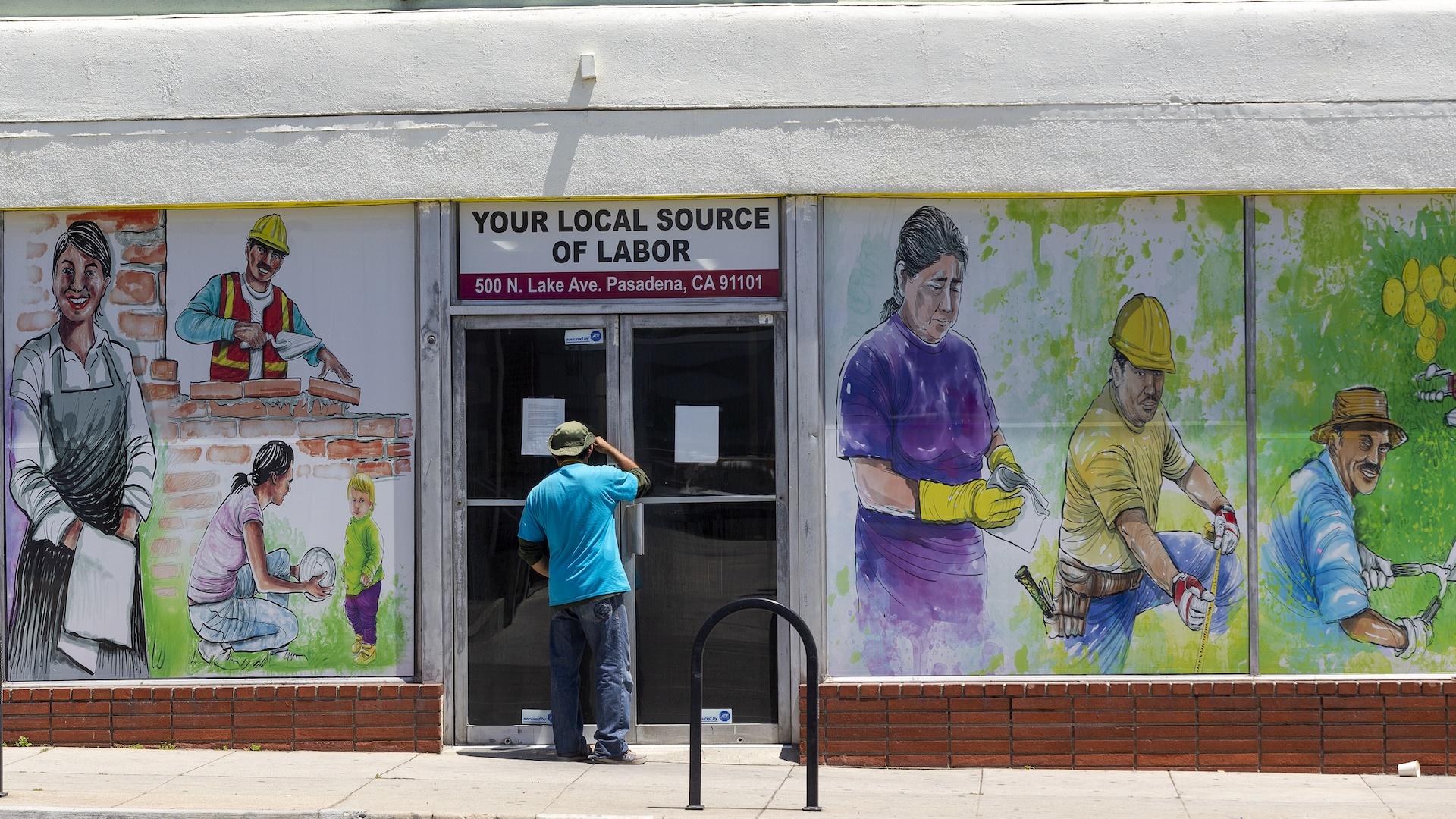 In this May 7, 2020, file photo, a person looks inside the closed doors of the Pasadena Community Job Center in Pasadena, Calif., during the coronavirus outbreak. (AP Photo/Damian Dovarganes, File)