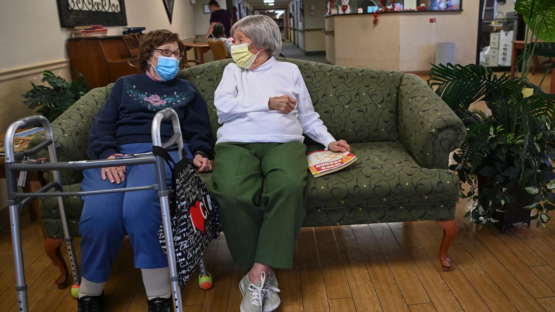 Carmela Sileo, left, and Susan McEachern sit next to each other and talk in the dayroom Wednesday, Feb. 3, 2021, at Arbor Springs Health and Rehabilitation Center in Opelika, Ala. (AP Photo / Julie Bennett)