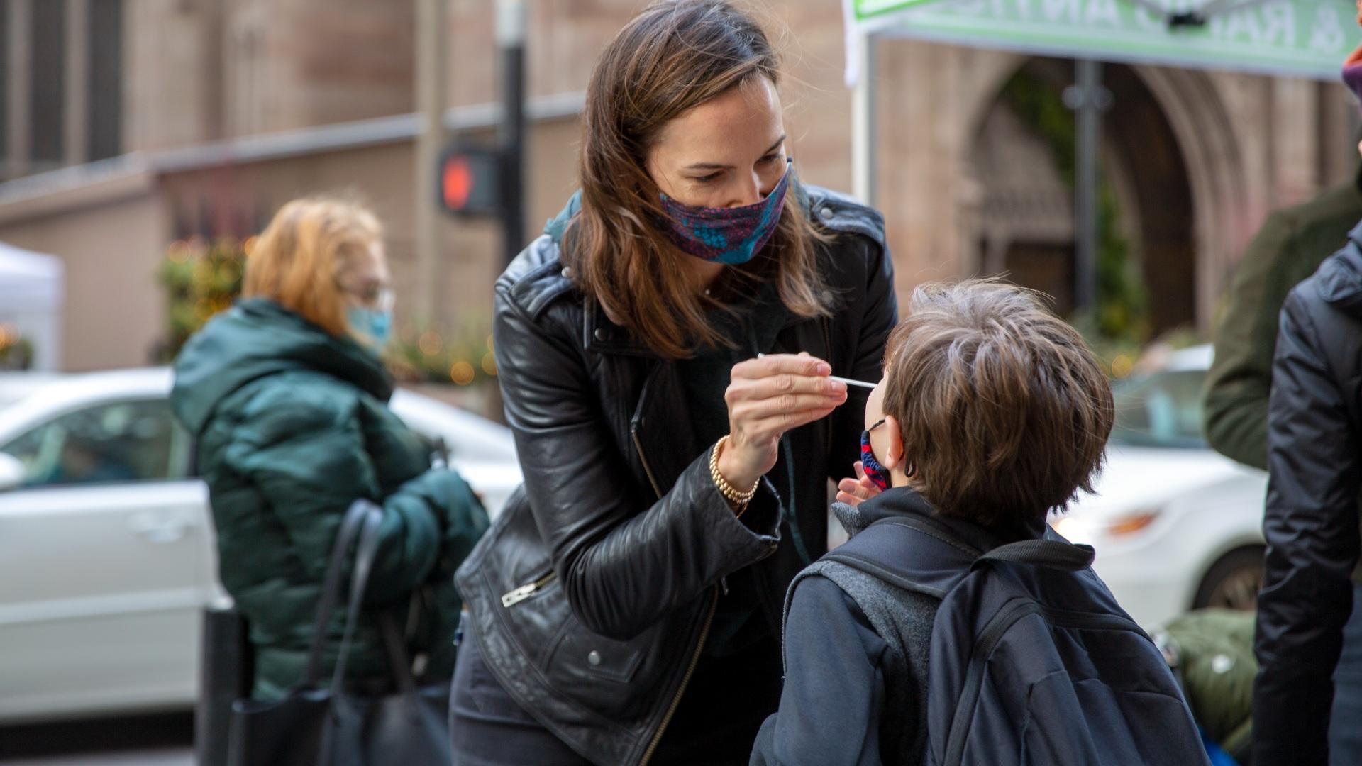 Katie Lucey administers a COVID-19 test on her son Maguire at a PCR and Rapid Antigen COVID-19 coronavirus test pop up on Wall Street in New York on Thursday, Dec. 16, 2021. (AP Photo / Ted Shaffrey)