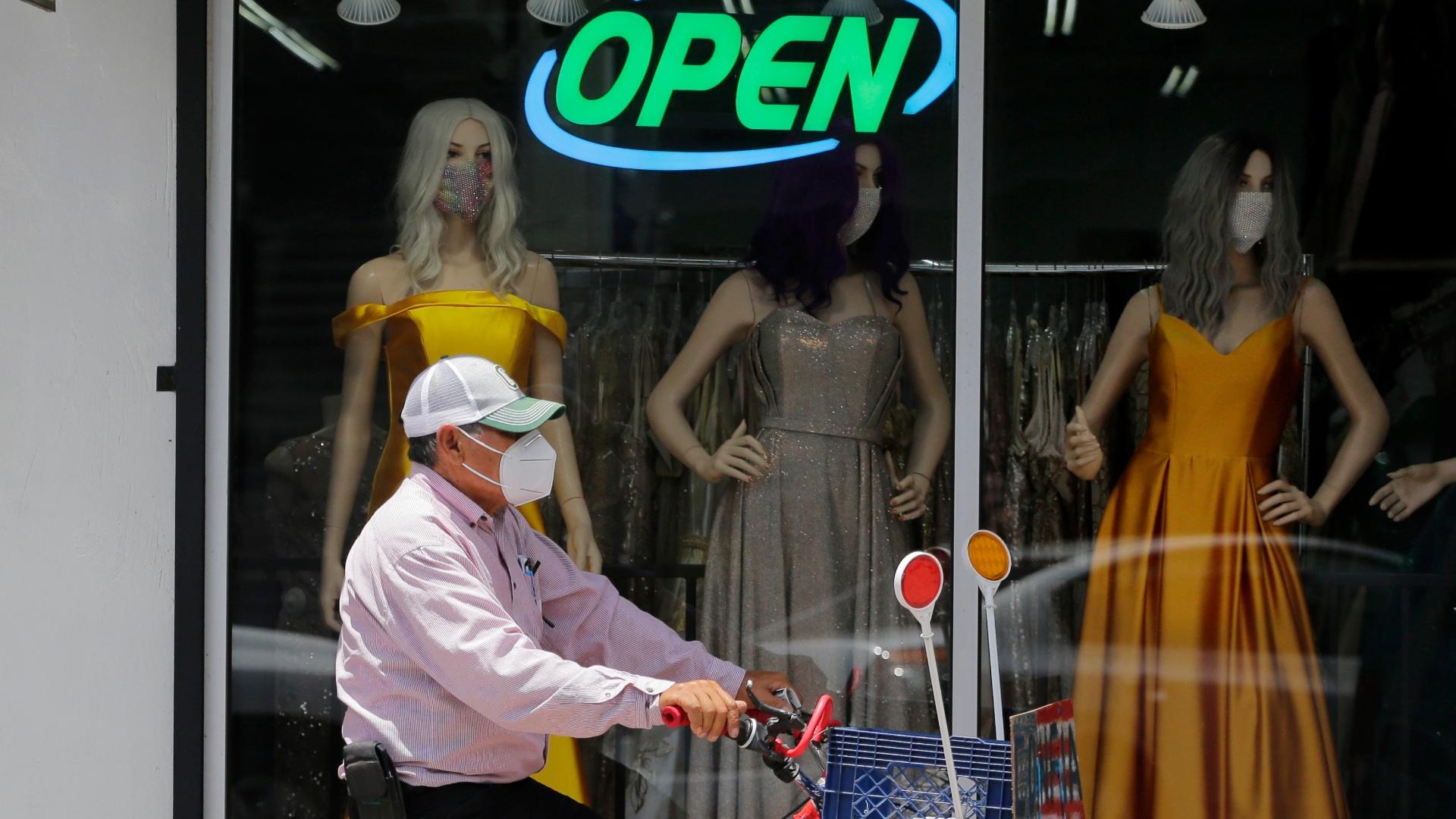In this July 30, 2020, file photo, a cyclist passes a display window with mask covered mannequins at a dress store in McAllen, Texas. (AP Photo / Eric Gay, File)