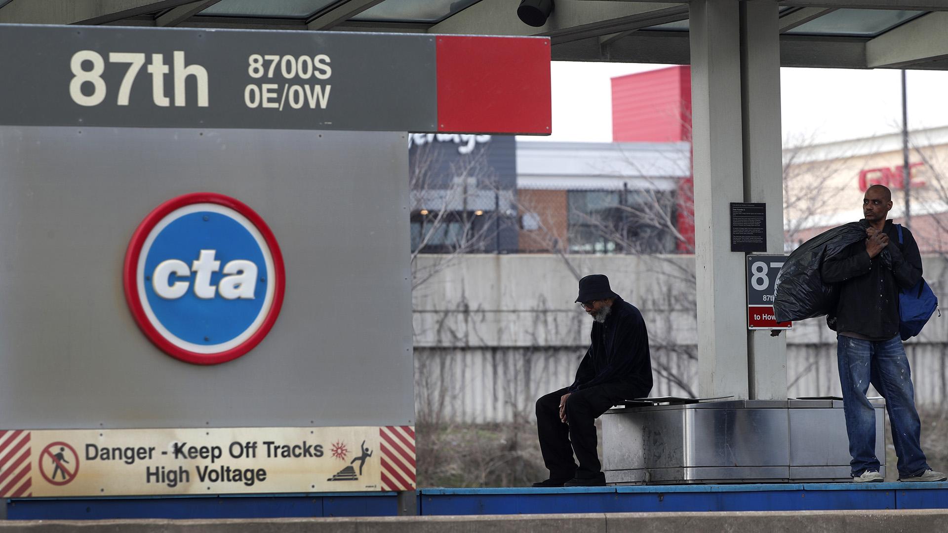 In this April 7, 2020, file photo, two men wait for a Chicago Transit Authority Red Line train on Chicago's South Side. (AP Photo / Charles Rex Arbogast, File)