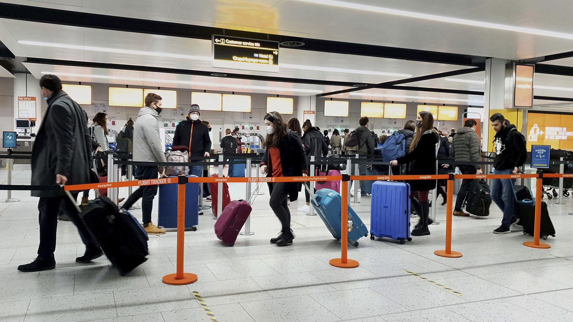 In this Dec. 20, 2020, file photo, passengers queue for check-in at Gatwick Airport in West Sussex, England, south of London. (Gareth Fuller / PA via AP)