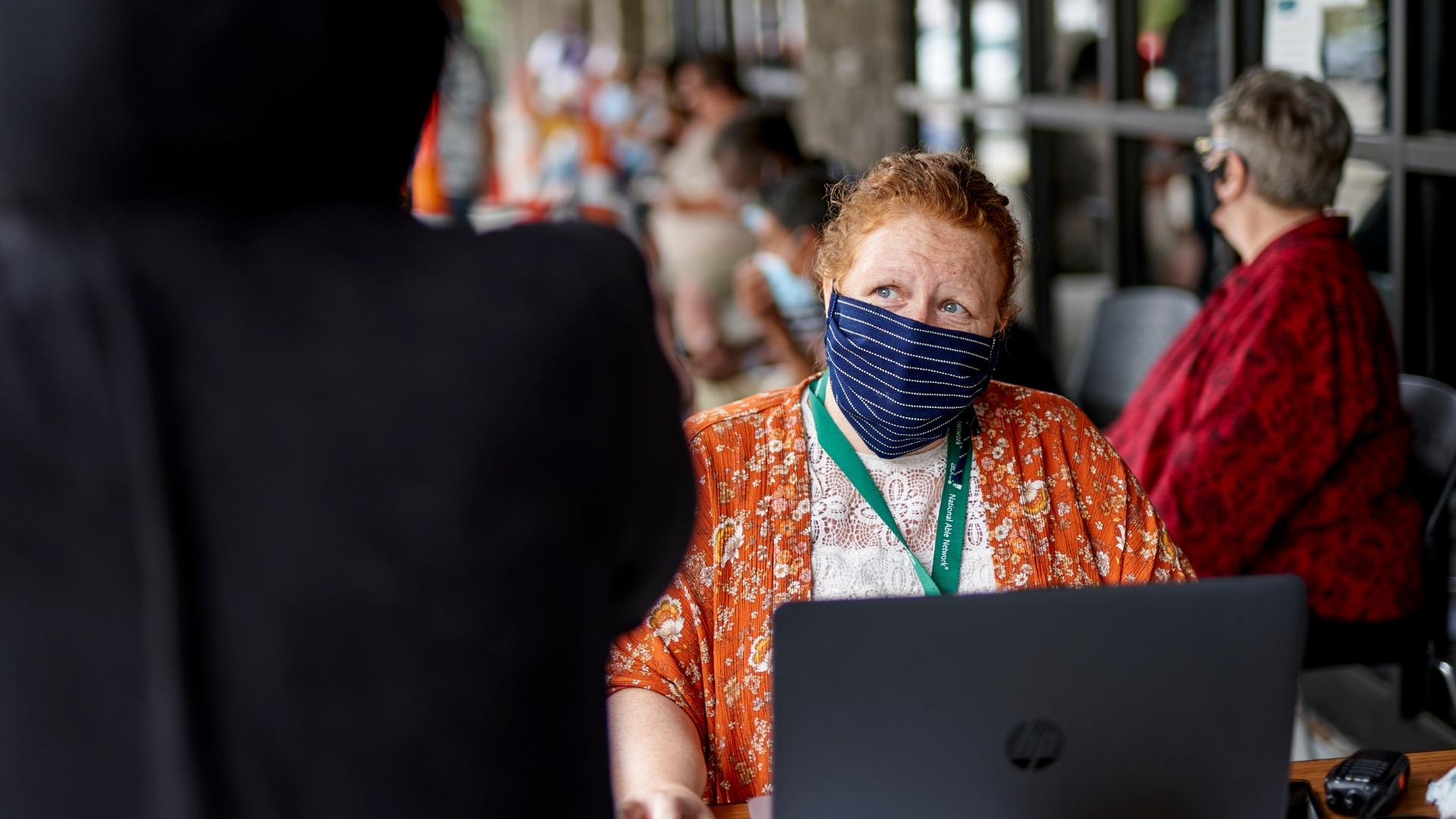 In this July 15, 2020, file photo, One-stop operator Vickie Gregorio with the Heartland Workforce Solutions talks to a jobseeker outside the workforce office in Omaha, Neb., as others seeking employment wait behind her. (AP Photo / Nati Harnik, File)