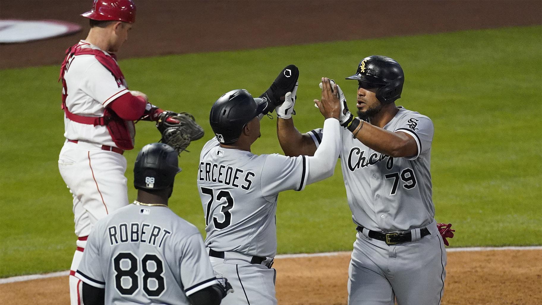 Chicago White Sox's Jose Abreu (79) high-fives Yermin Mercedes (73) after hitting a grand slam during the third inning of an MLB baseball game against the Los Angeles Angels Friday, April 2, 2021, in Anaheim, Calif. Mercedes, Tim Anderson, and Luis Robert (88) also scored. (AP Photo / Ashley Landis)