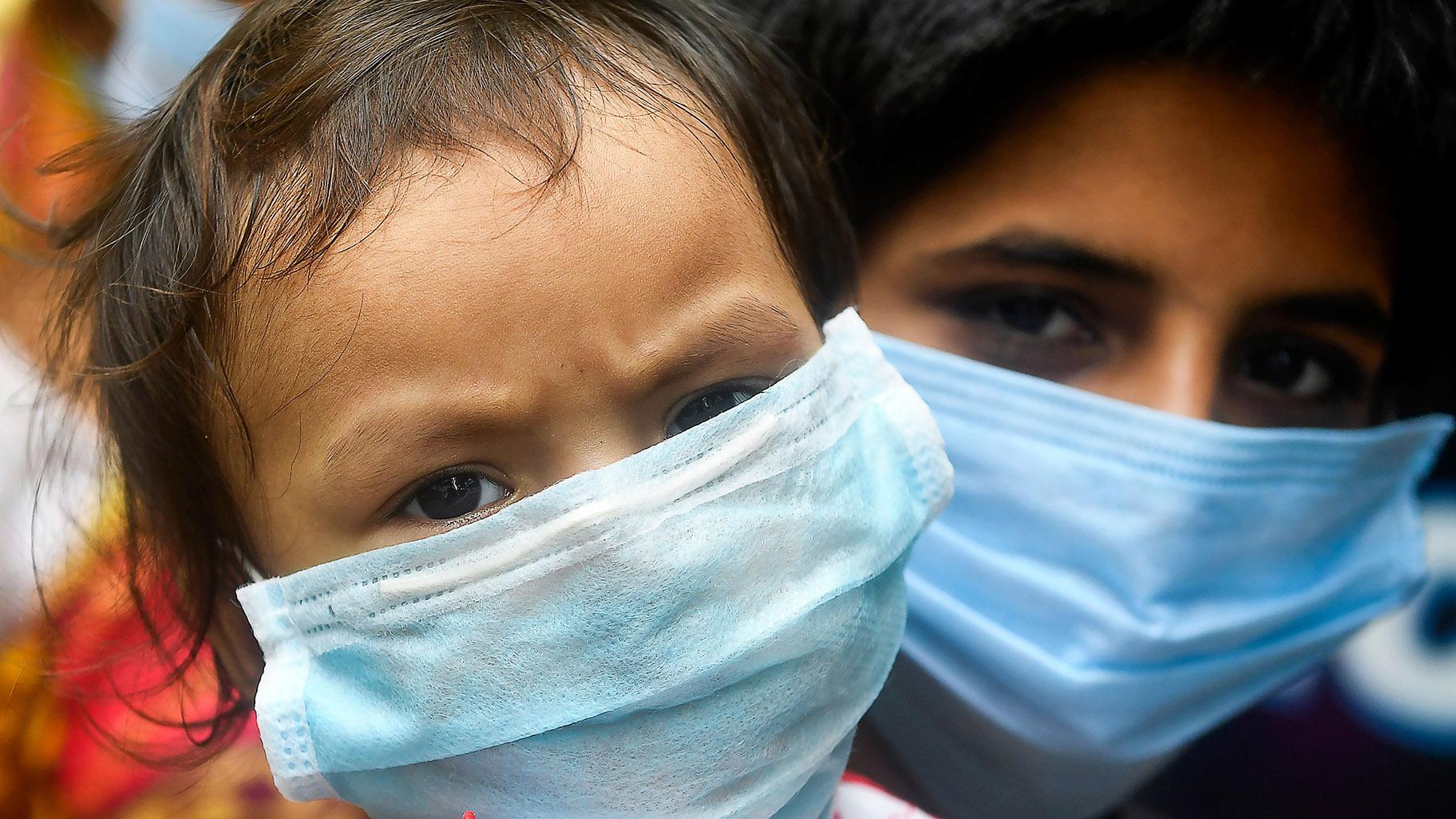 Children wearing face masks wait in a queue with others to take swab samples to test for the COVID-19 coronavirus, in Kolkata on July 28, 2020. (DIBYANGSHU SARKAR / AFP / AFP via Getty Images)