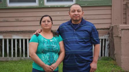 In this photo provided by Cristobal Francisquez, his parents Paulina and Marcos Francisco pose for a photo in front of their house in Sioux City, Iowa, Monday, May 25, 2020. They bought the home after years of working in a meatpacking plant and other food processing jobs. (Cristobal Francisquez via AP)
