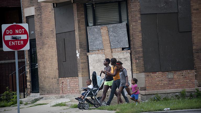 A group of girls walk in Englewood. This building is across the street from one of 50 Chicago Public Schools that closed in 2013. (Photo by Bill Healy)