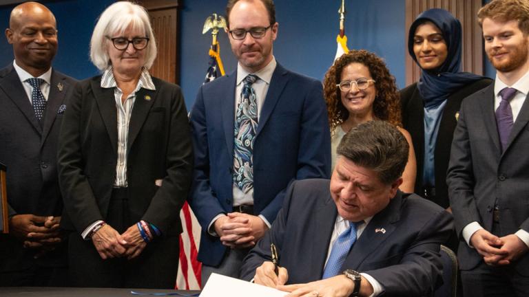Gov. JB Pritzker signs the Artificial Intelligence Safety Measures Act into law in Chicago on July 6, 2026, surrounded by lawmakers and advocates. (Maggie Dougherty / Capitol News Illinois)