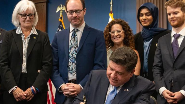 Gov. JB Pritzker signs the Artificial Intelligence Safety Measures Act into law in Chicago on July 6, 2026, surrounded by lawmakers and advocates. (Maggie Dougherty / Capitol News Illinois)