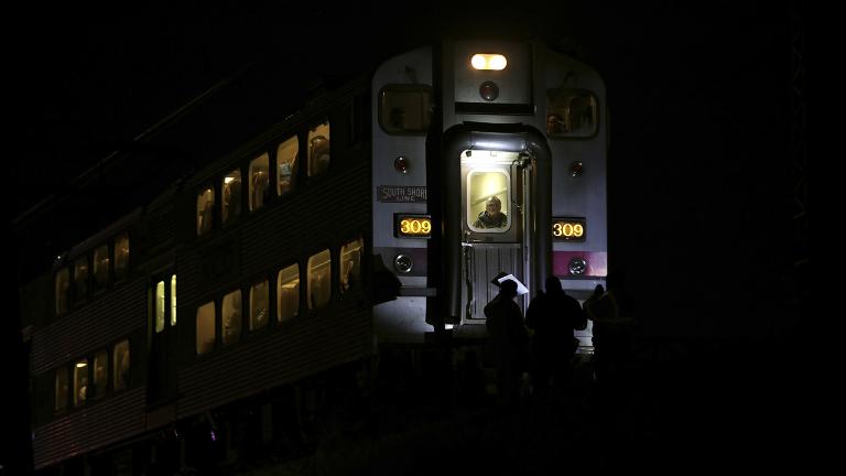 Passengers sit on a train while police officers work the scene where two officers were killed after they were struck Monday, Dec. 17, 2018 by a South Shore train near 103rd Street and Dauphin Avenue. (E. Jason Wambsgans / Chicago Tribune via AP)