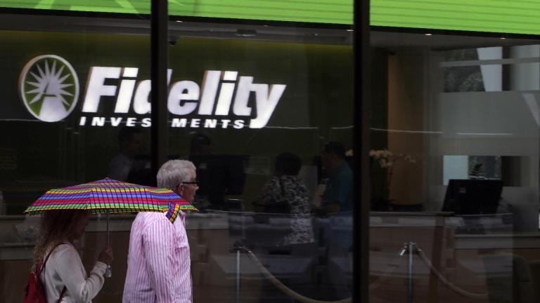 In this June 18, 2019, photo people walk past Fidelity Investments news scroll board, showing a favorable outlook in the US stock markets, in the Financial District of Boston. (AP Photo / Charles Krupa)