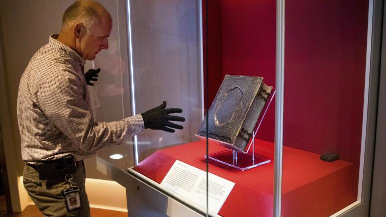 Mike Casey, exhibits project manager at the Abraham Lincoln Presidential Museum, moves the newly acquired Bible that belonged to Abraham Lincoln in his final year of life, into an exhibit at the museum following a press conference announcing its arrival Thursday, June 20, 2019, in Springfield, Illinois. (Ted Schurter / The State Journal-Register via AP)