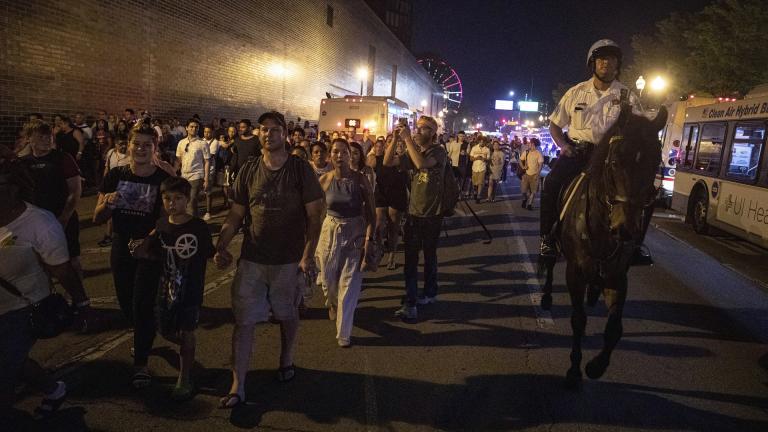 In this Thursday, July 4, 2019 photo, A Chicago Police Department officer guards people as they stream out of Chicago’s Navy Pier after reports of stabbings and threatening injuries after the 4th of July celebrations. (AP Photo / Amr Alfiky)