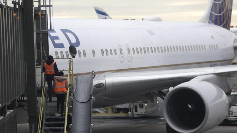 In this Jan. 23, 2019, photo employees walk up a ramp toward a ramp where a United Airlines jet is parked at a gate Newark Liberty International Airport in Newark, New Jersey. (AP Photo / Julio Cortez)