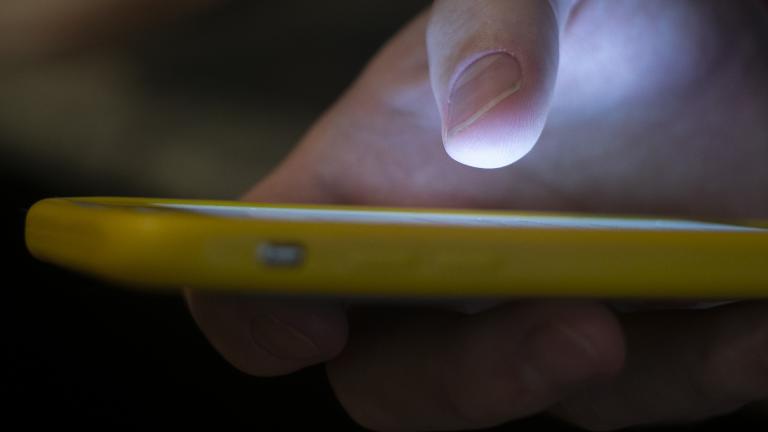 In this Sunday, Aug. 11, 2019, photo, a man uses a cell phone in New Orleans. With suicides on the rise, the government wants to make the national crisis hotline easier to reach. (AP Photo / Jenny Kane)